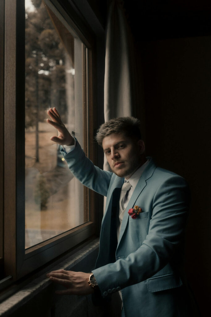 Brudgum star vid fonster under forberedelserna.