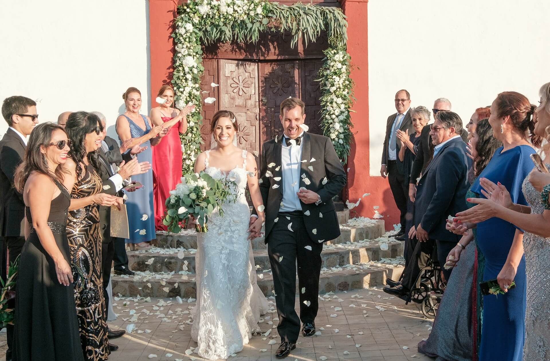 Brudpar lämnar vigsel i stadshusmiljö medan gäster kastar blomblad – bröllopsfotograf Malmö