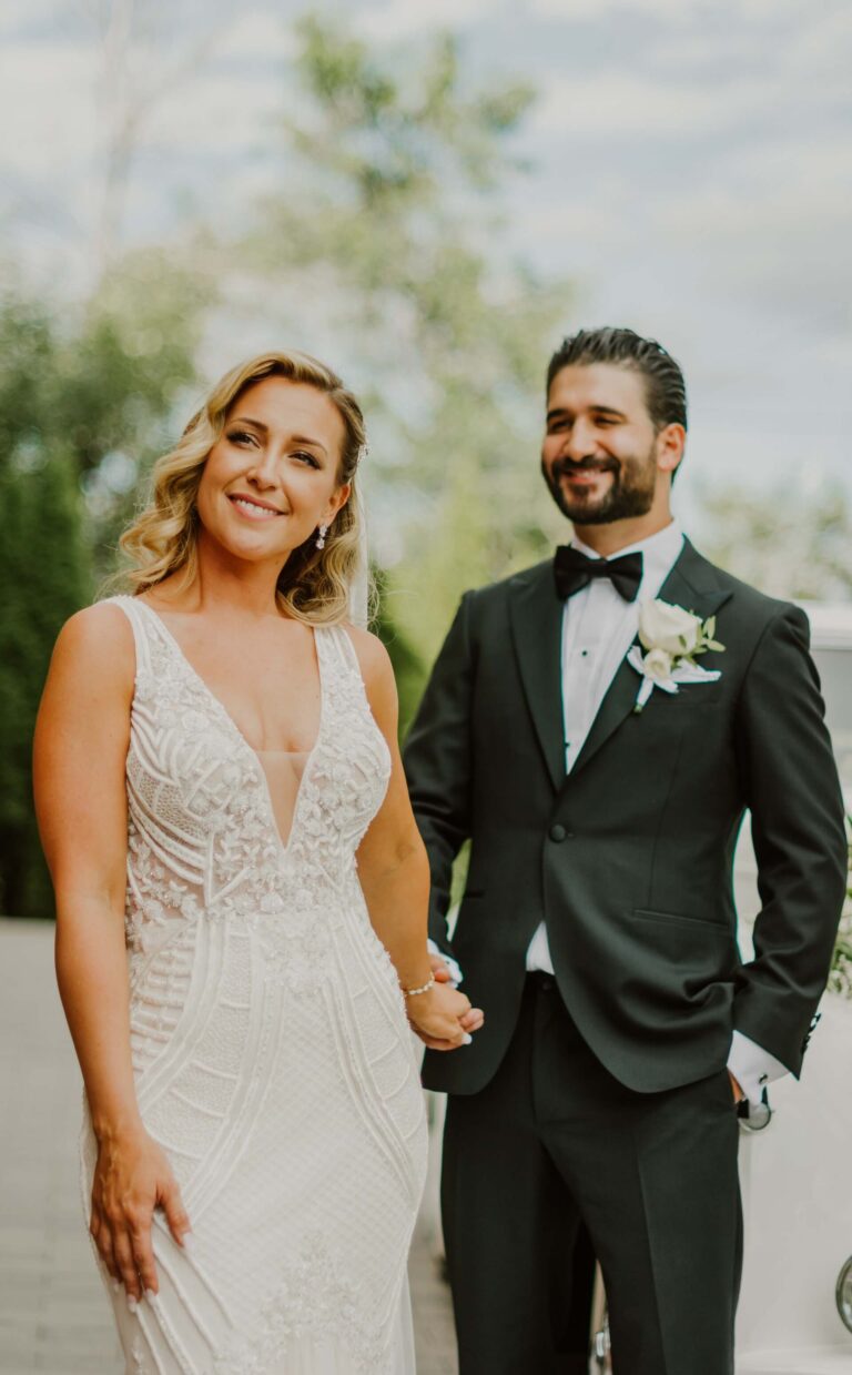 Brud och brudgum håller varandra i handen under ett porträtt på bröllopsdagen